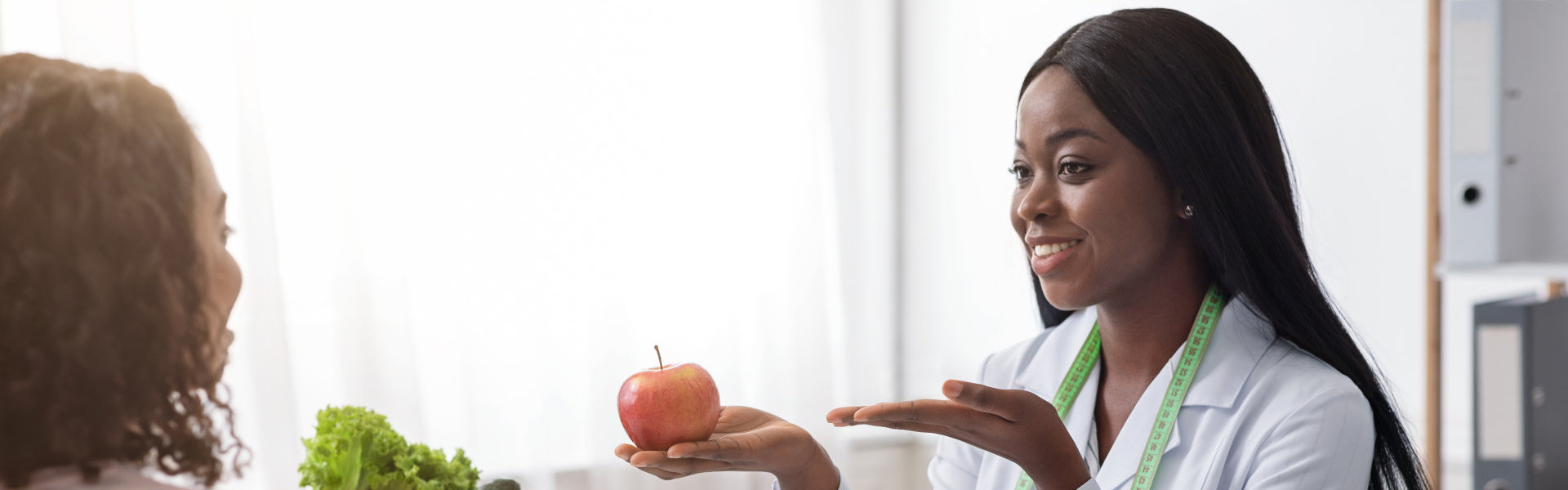 woman nutritionist recommending female patient fresh fruits